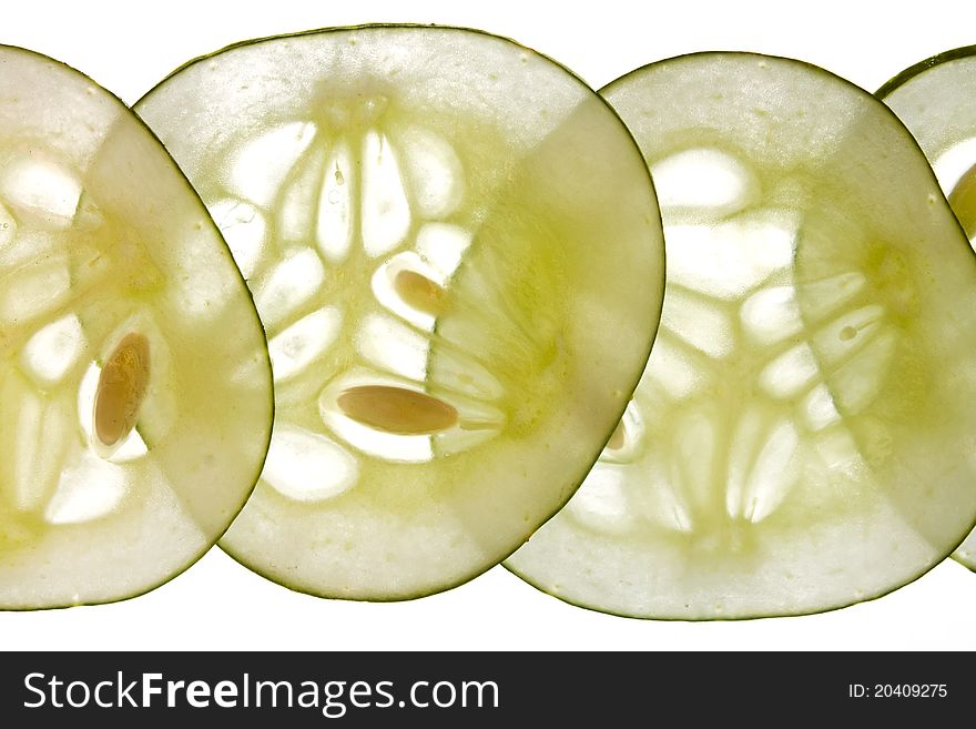 Thinly sliced fresh cucumber backlit against a white background. Thinly sliced fresh cucumber backlit against a white background