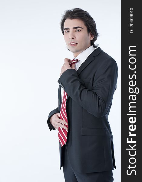 Confident young business man arranging his tie
