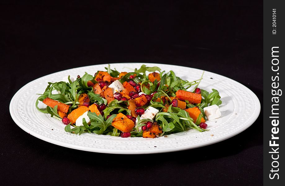 Pumpkin and pomegranate salad on the black background