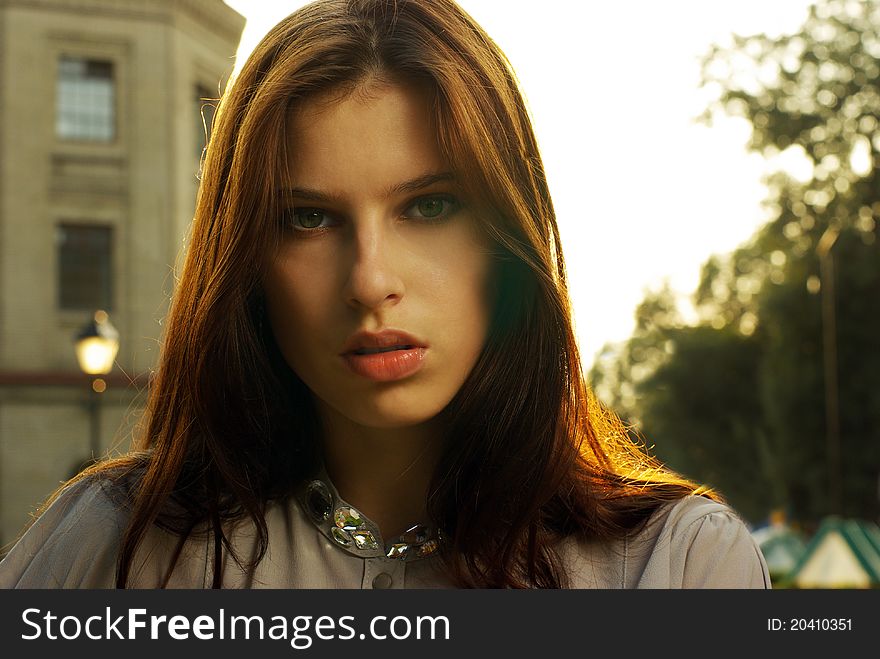 Portrait of a beautiful woman posing at the city street in sunset back light