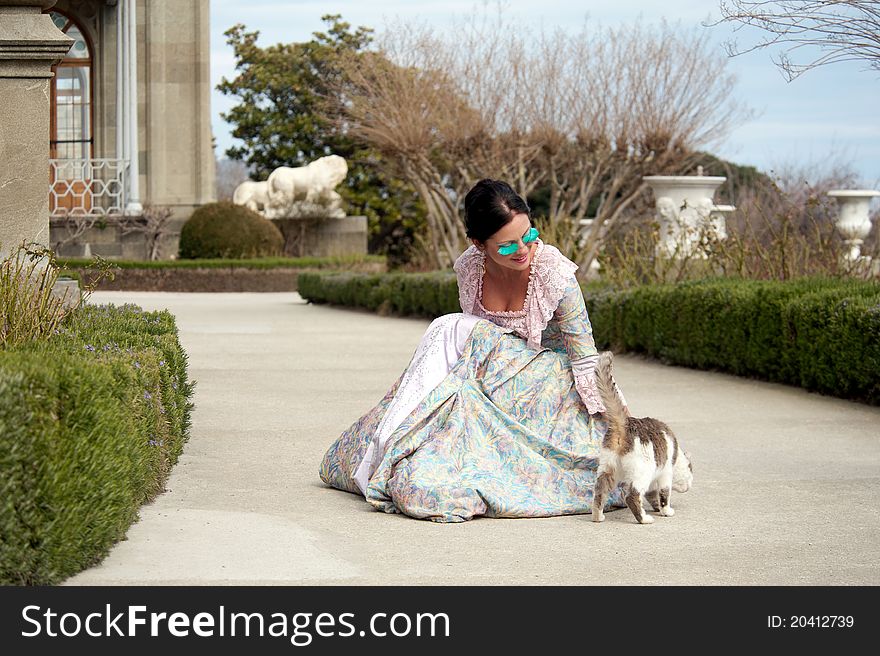 Woman in classical dress goes through the alley next to the cat. Woman in classical dress goes through the alley next to the cat