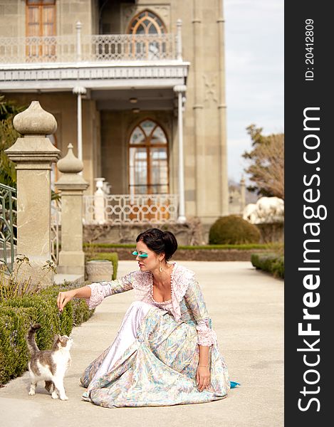 Woman in classical dress goes through the alley next to the cat. Woman in classical dress goes through the alley next to the cat