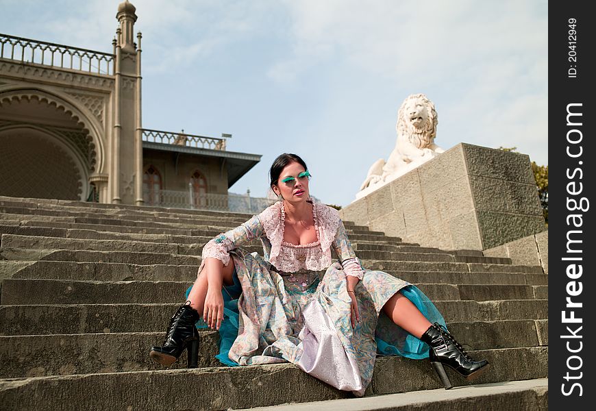 Woman in classical dress standing on the stairs near the castle