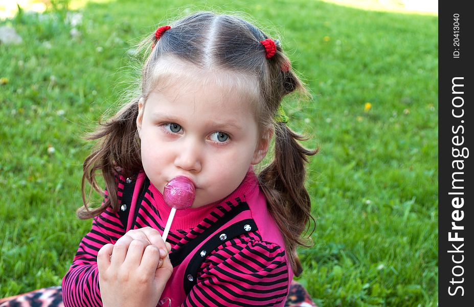 Beautiful little blonde girl with candy outdoors. Beautiful little blonde girl with candy outdoors