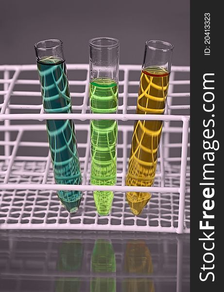 Closeup of three test-tubes with colorful fluids in a stand, front view with reflections. Closeup of three test-tubes with colorful fluids in a stand, front view with reflections