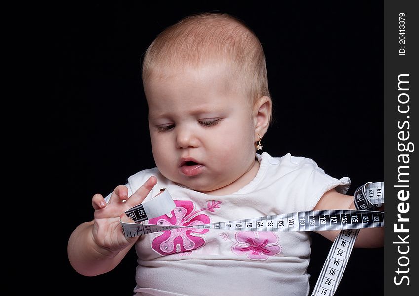 Little baby girl measuting with a meter on black background. Little baby girl measuting with a meter on black background