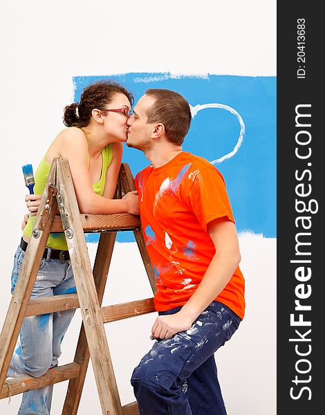 Young man kissing his girlfriend during home renovation. Young man kissing his girlfriend during home renovation