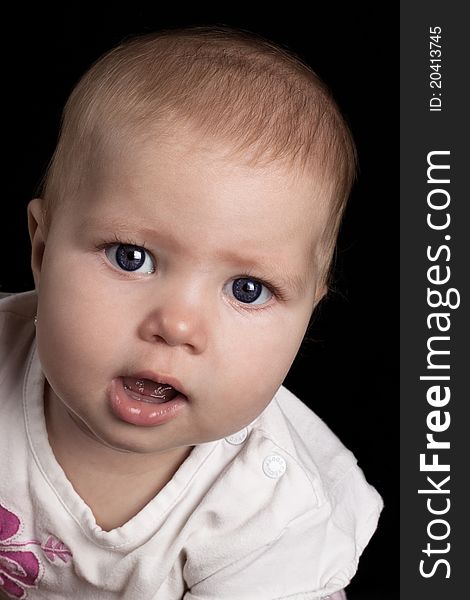 Cute little baby girl portrait closeup on black background