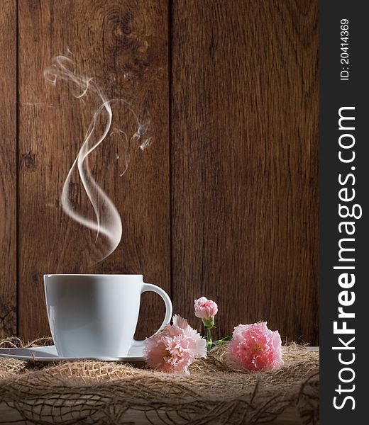 Cup of coffee with flowers on wooden background