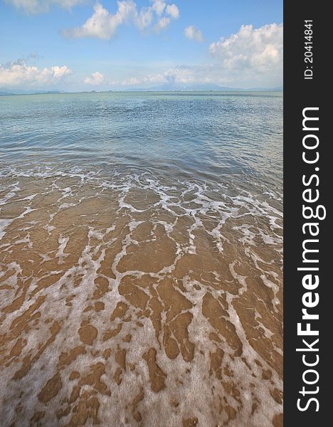 White water foam extending on sea beach, and different color of sky, water and sand, shown as beach landscape. White water foam extending on sea beach, and different color of sky, water and sand, shown as beach landscape.