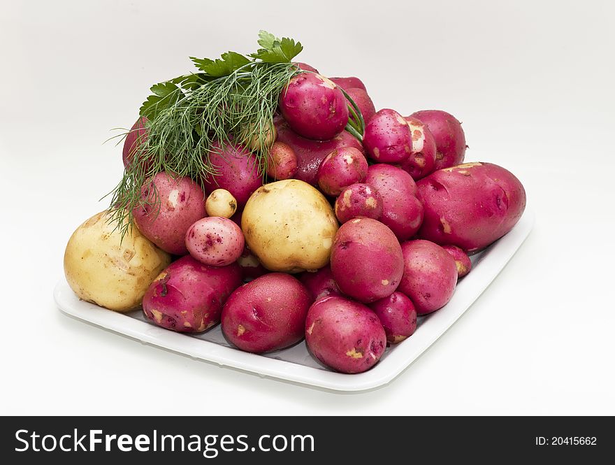 Young white and red potatoes, displayed on the plate with some herbs
