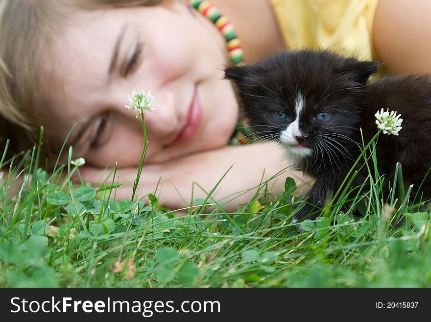 A girl and a kitten are on the grass