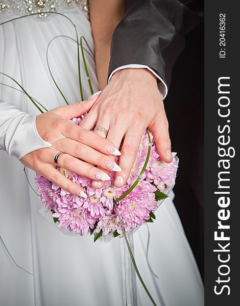 Bride and groom hands with wedding rings and bouquet of chrysanthemums