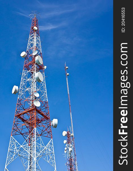 Broadcaster or transmitter tower with telecommunication satellites on blue sky