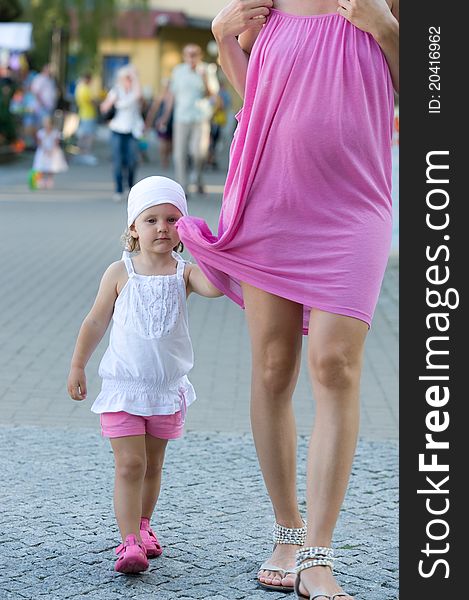 Little Girl Is Holding Mother Dress During Walk