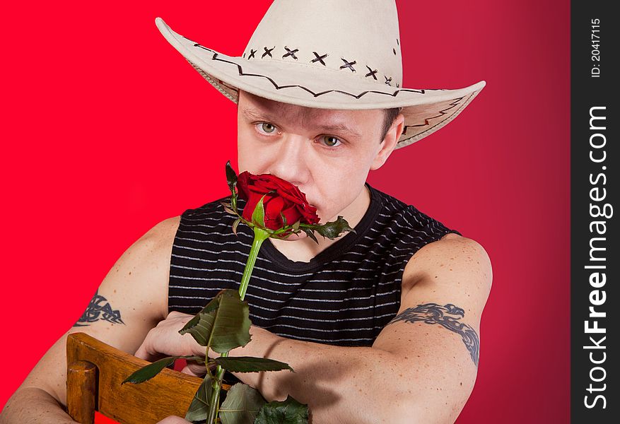 A muscular man in a cowboy hat with red rose