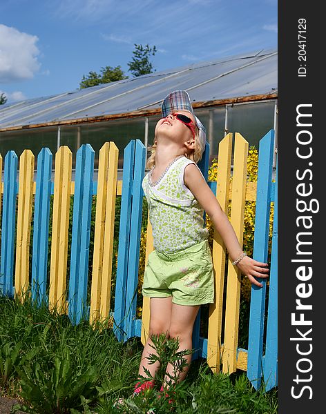 Girl stands near a colour fence and looks upward. Girl stands near a colour fence and looks upward