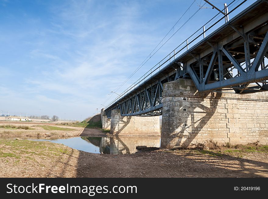 Old railway iron bridge over a narrow stream in an arable landscape in Ciudad Real Province, Spain. Old railway iron bridge over a narrow stream in an arable landscape in Ciudad Real Province, Spain