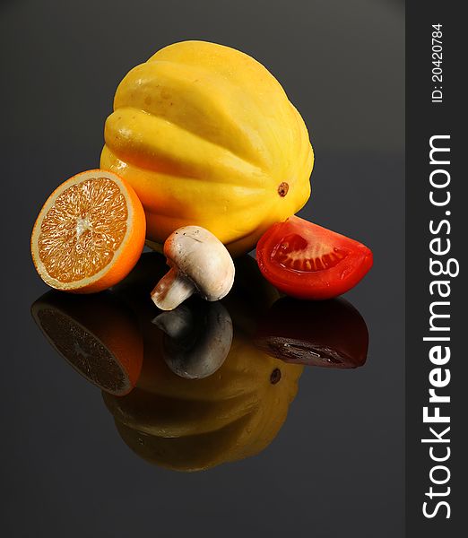 Slice of orange, squash; mushroom and tomato on reflective table. Slice of orange, squash; mushroom and tomato on reflective table