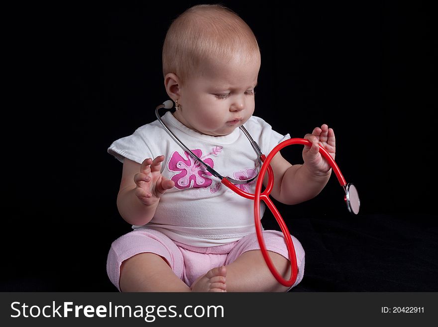 Little baby girl playing with red stethoscope. Little baby girl playing with red stethoscope