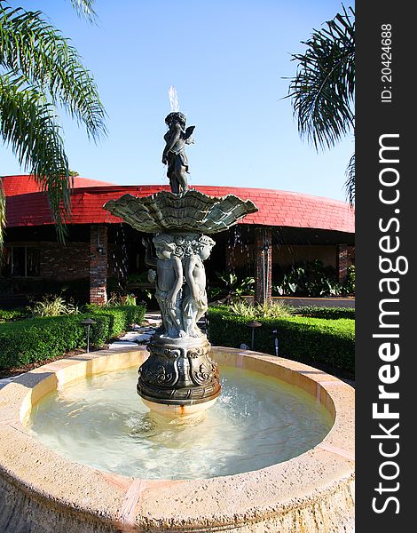 Classic water fountain in front of building. Tropical location on a sunny day.