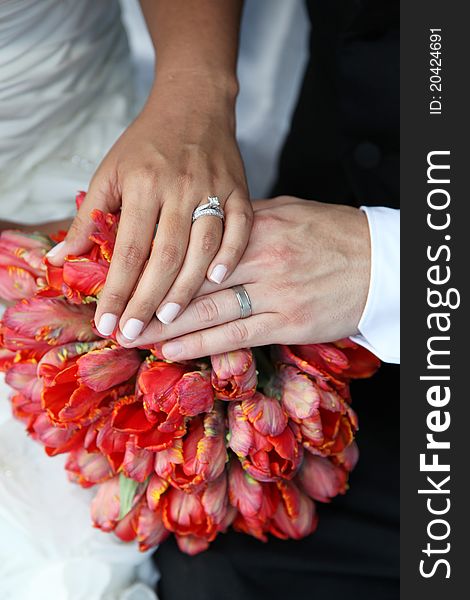 Bride and Grooms hands and rings on red flower bouquet. Bride and Grooms hands and rings on red flower bouquet.