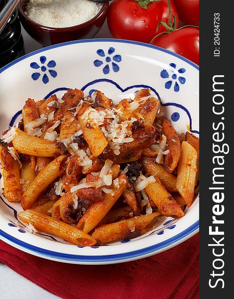 A plate of fried maccheroni with tomato, bacon and olive oil. A plate of fried maccheroni with tomato, bacon and olive oil