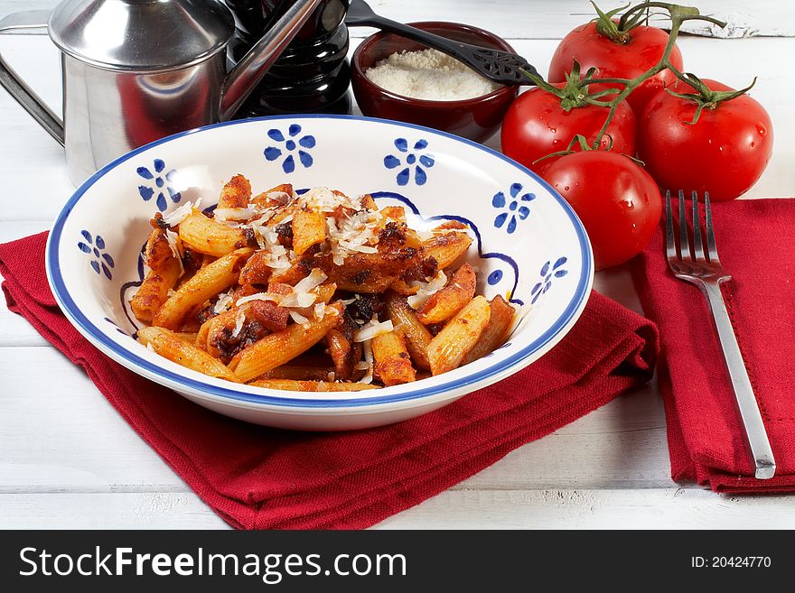 A plate of fried maccheroni with tomato, bacon and olive oil. A plate of fried maccheroni with tomato, bacon and olive oil