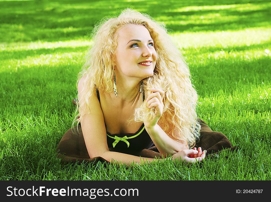Outdoor portrait of young cheerful girl lying on the green grass. Outdoor portrait of young cheerful girl lying on the green grass