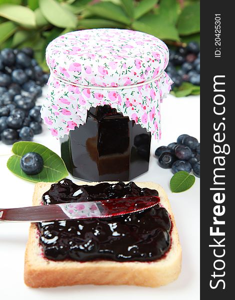 A glass of homemade blueberry jam with fresh fruits and leaves