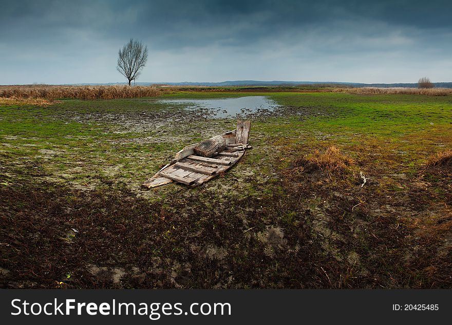 An old boat near the swamps and stormy sky. An old boat near the swamps and stormy sky