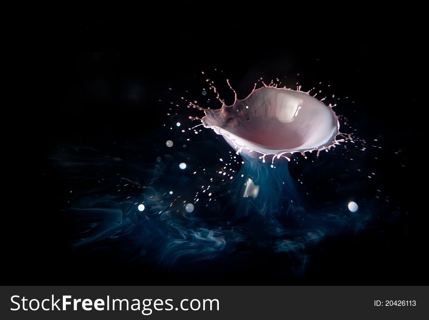 A high-speed photo of a 2 drops of red-tinted cream falling into a bowl of blue tinted water. A high-speed photo of a 2 drops of red-tinted cream falling into a bowl of blue tinted water.