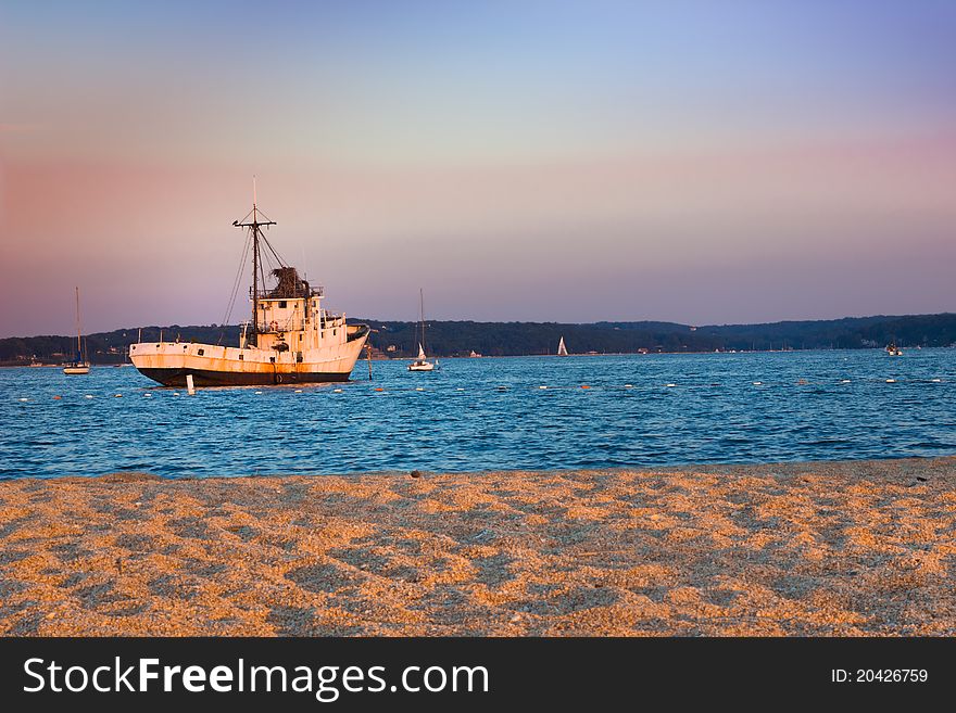 Fishing boat at the end of the day with golden sun falling on the beach