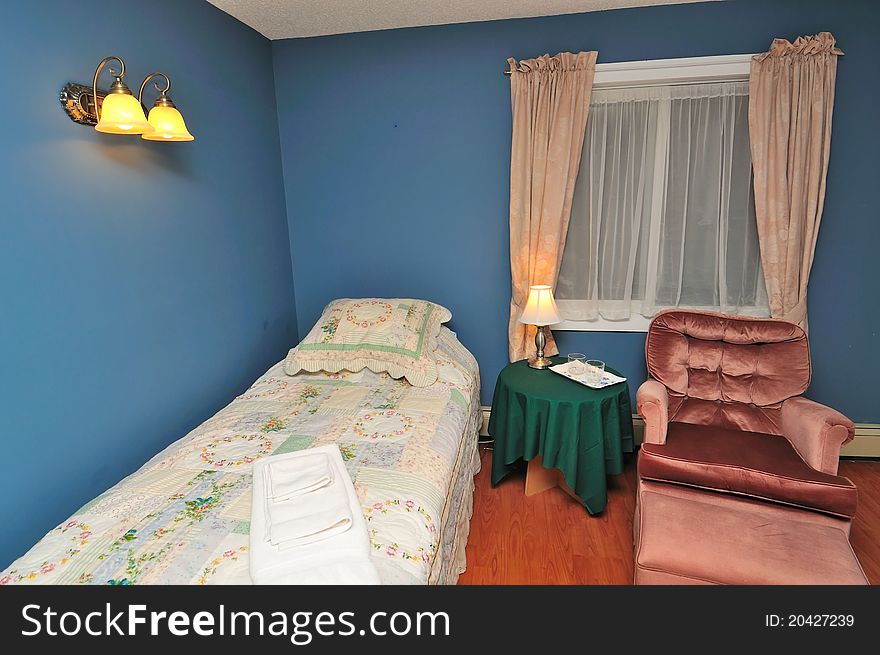 Lluxurious hotel bedroom with single bed and armchair.