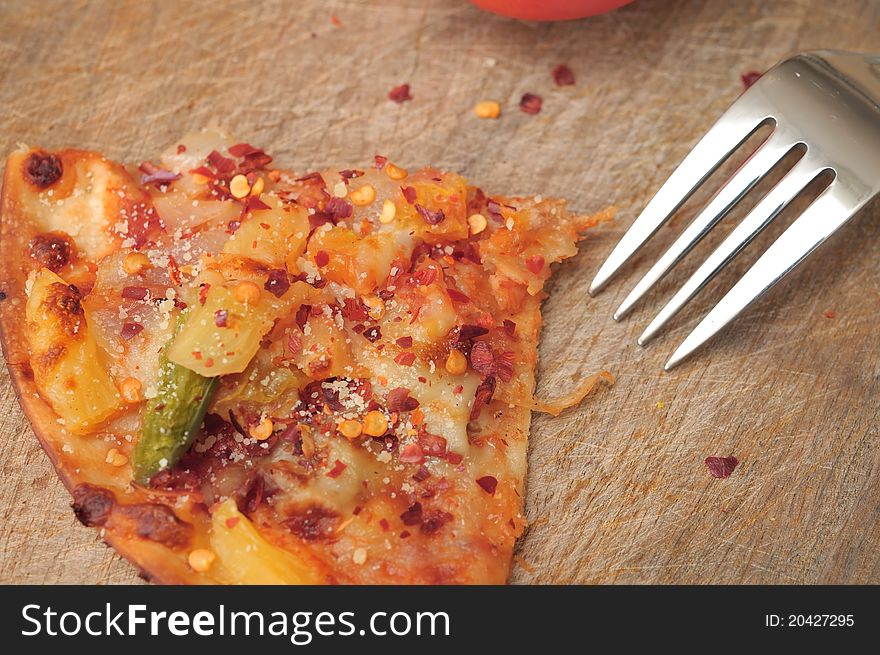 Closeup shot of single pizza slice with fork on wooden background. Closeup shot of single pizza slice with fork on wooden background.