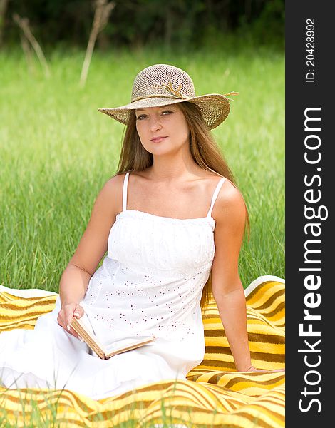 Young beautiful girl with book in nature in hat. Young beautiful girl with book in nature in hat