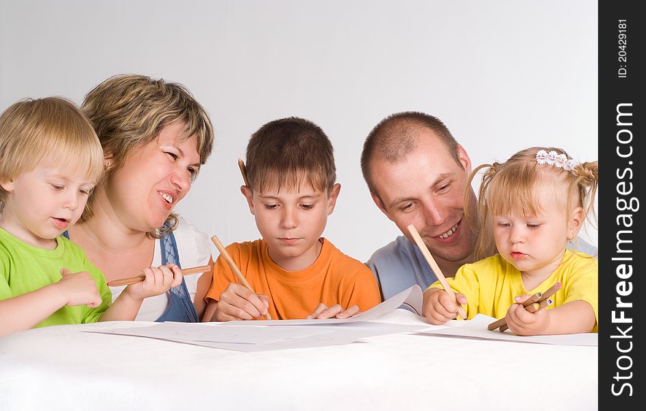 Happy family drawing at the table on a white