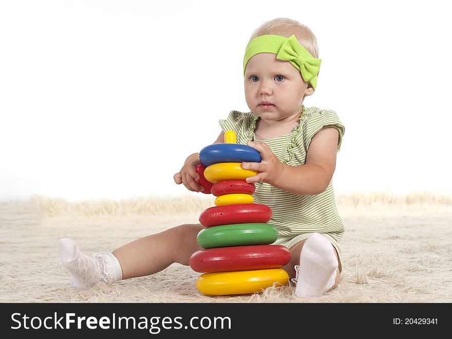 Little girl playing on a carpet with toy