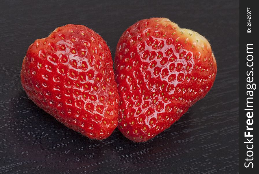 Two fresh strawberry on black wooden background