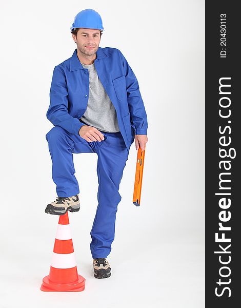 Builder with foot on traffic cone.