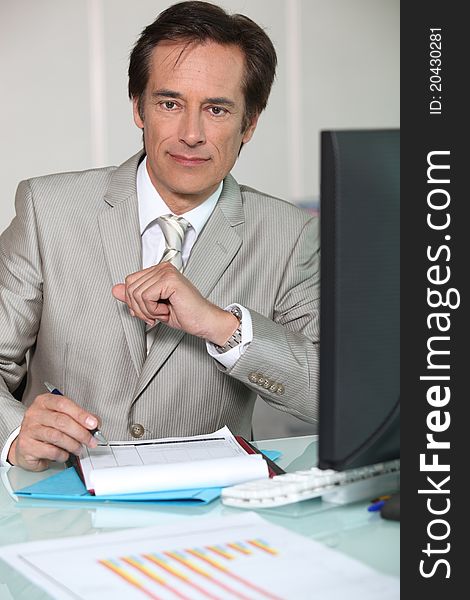 Businessman filling out a form at his desk. Businessman filling out a form at his desk