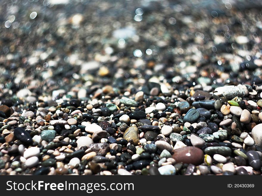 Colored wet sea stones lay down on the seaside. Colored wet sea stones lay down on the seaside