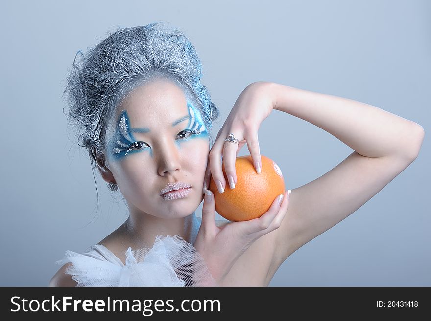 Portrait of woman with creative makeup and orange in her hands. Portrait of woman with creative makeup and orange in her hands