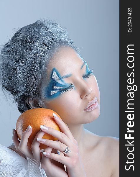 Portrait of woman with creative makeup and orange in her hands. Portrait of woman with creative makeup and orange in her hands