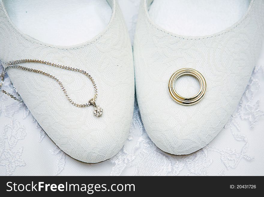 Engagement rings lie on the bride's shoes. Engagement rings lie on the bride's shoes