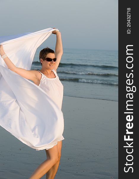 Pregnant woman with white shawl is running on the beach. Pregnant woman with white shawl is running on the beach