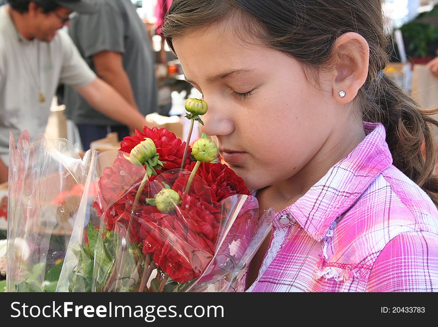 Girl smelling a bouquet of flowers at an open air market. Girl smelling a bouquet of flowers at an open air market.