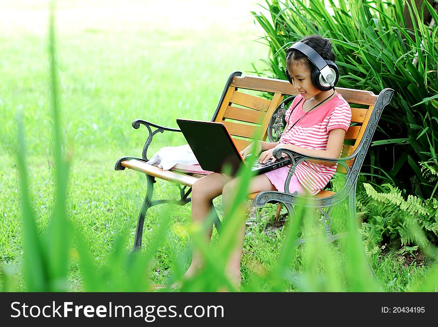 Girl listening to music from a laptop in the garden. Girl listening to music from a laptop in the garden