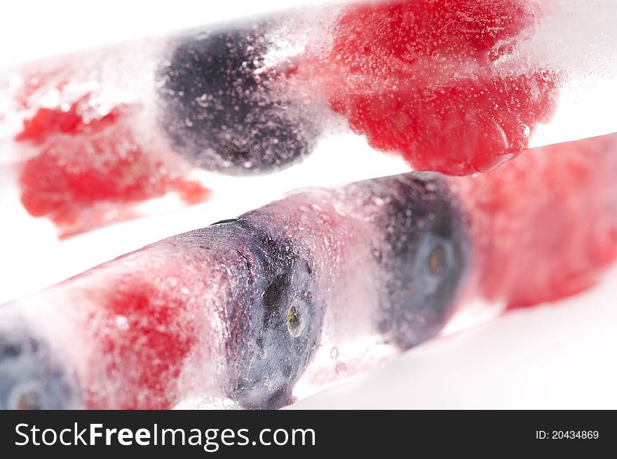 Raspberry and blackberry frozen in ice sticks on white