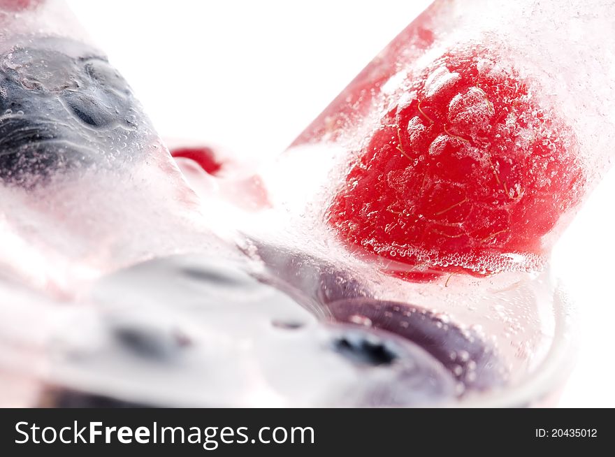 Raspberry and blackberry frozen in ice sticks on white